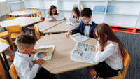 Schulkinder sitzen an den Tischen und Lesen