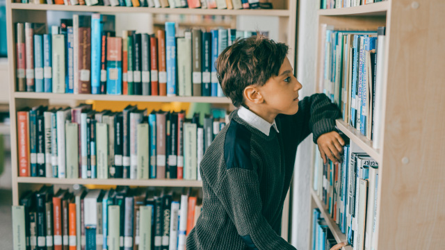 Junge starrt auf Bücherregal