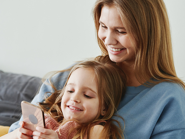 Mutter und Kind lesen am Smartphone